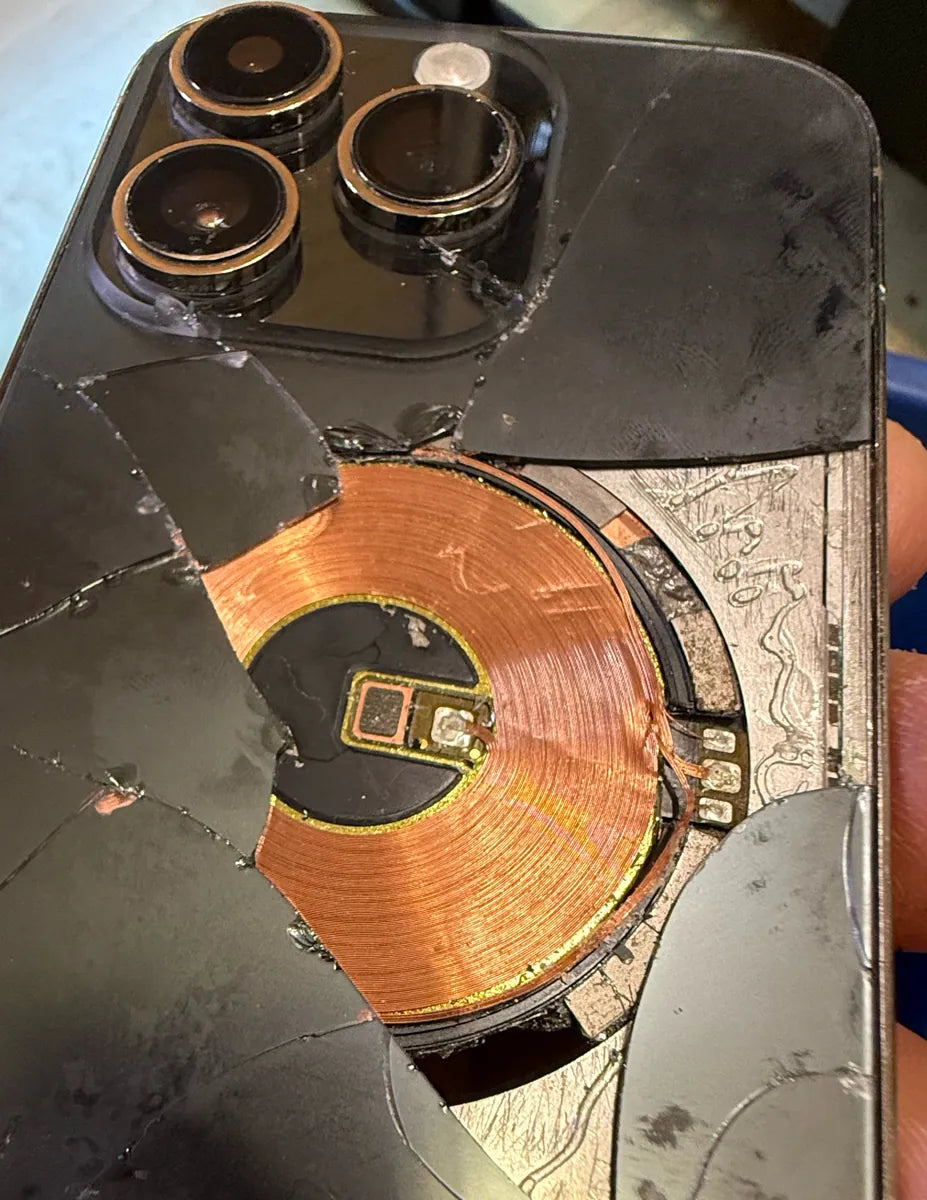 Close-up of cracked iPhone Pro back glass and exposed charging coil before repair at Franchitti's Fix, serving South Park and Golden Hill